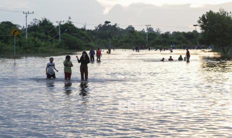 Sejumlah warga berjalan di area banjir yang menggenangi jalur trans Kalimantan Kasongan, Kabupaten Katingan, Kalimantan Tengah, Kamis (9/9/2021). Sebanyak tiga titik banjir luapan Sungai Katingan dengan tinggi 30-60 centimeter itu merendam jalur trans Kalimantan Kasongan yang merupakan jalan nasional penghubung Palangkaraya dengan sejumlah Kabupaten/Kota di Kotawaringin Timur. 