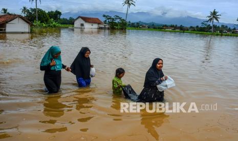 Sejumlah warga berjalan menerobos banjir di Desa Tanjungsari, Kecamatan Sukaresik, Kabupaten Tasikmalaya, Jawa Barat, Kamis (14/1/2021). Akibat intensitas hujan yang tinggi, luapan air Sungai Citanduy dan Cikidang meluas hingga merendam 400 rumah warga di Dusun Bojongsoban dan Hegarsari dengan ketinggian mencapai sekitar 80 sentimeter hingga 1,5 meter. 