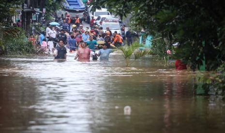 Sejumlah warga berjalan saat banjir di Villa Pamulang, Pondok Petir, Depok, Jawa Barat, Sabtu (16/7/2022). Tanggul aliran sungai jebol dan hujan deras yang mengguyur pada Jumat (15/7) malam hingga pagi hari mambuat air sungai di sekitar lokasi meluap menyebabkan banjir dengan ketinggian 1meter. 