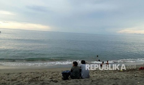 Sejumlah warga bermain air di Pantai Duduk, Kecamatan Batulayar, Kabupaten Lombok Barat, NTB pada Ahad (26/11) sore. Tampak dari kejauhan terlihat pemandangan Gunung Agung di Bali yang terlihat gelap.