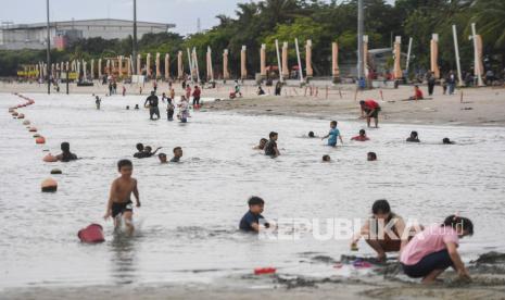 Sejumlah warga bermain di area pantai Taman Impian Jaya Ancol, Jakarta, Ahad (3/4/2022). Destinasi wisata Taman Impian Jaya Ancol akan tutup lebih awal, yakni pukul 15.00 WIB, pada H-1 Idul Fitri.