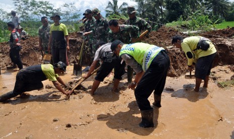 Sejumlah warga bersama tim SAR, anggota TNI dan polisi menyingkirkan timbunan tanah longsor yang menutup jalan antar desa di kawasan lereng gunung Sumbing Desa Kalegen, Bandongan, Magelang, Jawa Tengah, Selasa (15/12). 