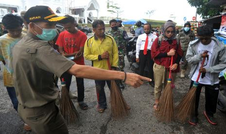 Sejumlah warga bersiap menjalani sanksi sosial menyapu jalan karena tidak menggunakan masker di Pantai Padang, Sumatera Barat, Senin (21/9/2020). Pemkot Padang mulai menerapkan aturan Perda Adaptasi Kebiasaan Baru (AKB) berupa sanksi sosial, denda dan kurungan penjara bagi warga yang tidak mematuhi protokol pencegahan COVID-19 di antaranya wajib menggunakan masker saat di luar rumah.