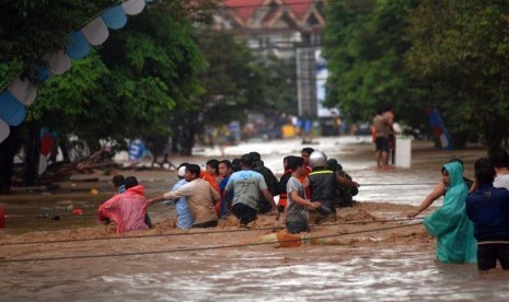   Sejumlah warga berusaha menyeberangi banjir menggunakan tali di Kelurahan Wenang, Manado, Sulawesi Utara, Rabu (15/1).   (Antara/Fiqman Sunandar)