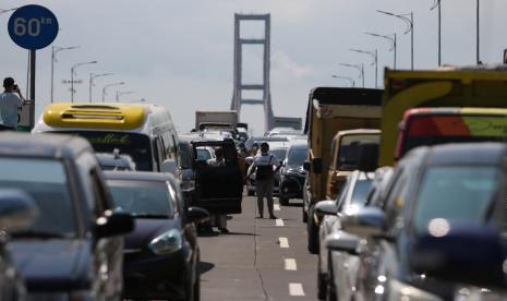 Sejumlah warga dari Pulau Madura keluar dari mobilnya saat mengantre masuk ke Surabaya di akses keluar Jembatan Suramadu, Surabaya, Jawa Timur, Minggu (6/6/2021). Petugas gabungan melakukan penyekatan di lokasi itu dan melakukan tes cepat antigen bagi warga dari Pulau Madura yang akan masuk ke Surabaya menyusul adanya peningkatan kasus COVID-19 di Madura.