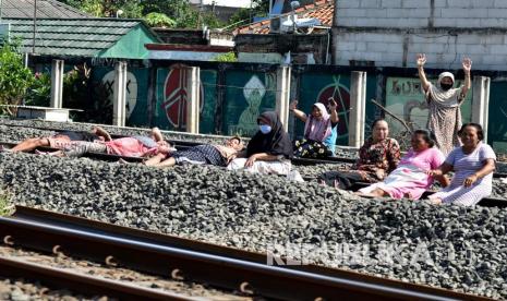 Sejumlah warga Kampung Buaran berjemur di atas rel kereta api di Bekasi, Jawa Barat.