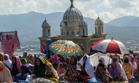 Sejumlah warga melaksanakan zikir bersama mengenang bencana gempa, tsunami, dan likuefaksi di depan Masjid Arqam Baburrahman yang amblas ke laut di Pantai Kampung Lere, Palu, Sulawesi Tengah, Sabtu (28/9/2019). Bencana yang terjadi Jumat, 28 September 2018 itu menelan korban lebih dari 4.780 jiwa dan merusakkan lebih dari 110 ribu rumah. 