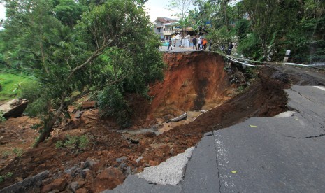 Sejumlah warga melihat jalan penghubung Kuningan-Majalengka yang amblas di desa Kawahmanuk, Kecamatan Darma, Kuningan, Jawa Barat, Jumat (17/2). 