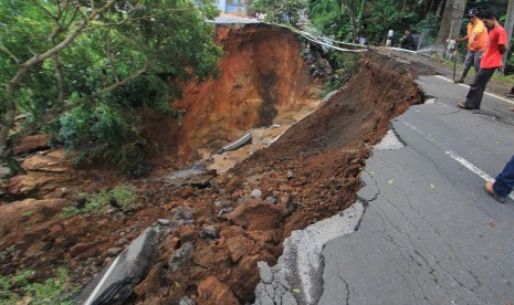 Sejumlah warga melihat jalan penghubung Kuningan-Majalengka yang amblas di desa Kawahmanuk, Kecamatan Darma, Kuningan, Jawa Barat, Jumat (17/2). 