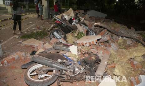 Sejumlah warga melihat reruntuhan bangunan akibat gempa yang menimpa kendaraan di salah satu pusat perbelanjaan di Denpasar, Bali, Ahad (5/8). 