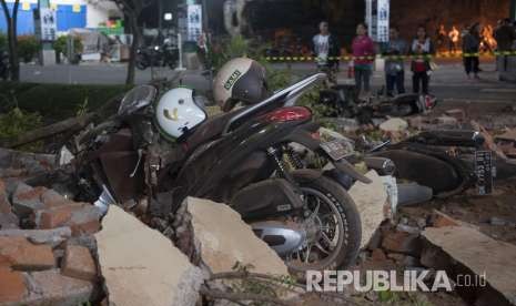 Sejumlah warga melihat reruntuhan bangunan akibat gempa yang menimpa kendaraan di salah satu pusat perbelanjaan di Denpasar, Bali, Ahad (5/8). 