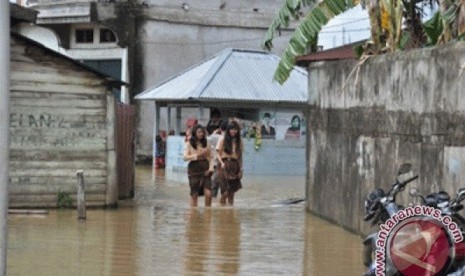 Sejumlah warga melintas banjir di Jambi, Ahad  (17/2). Hujan turun terus-menerus di Jambi dalam sepekan ini mengakibatkan debit air sungai naik sehingga rumah warga di pinggiran Sungai Batanghari terendam.