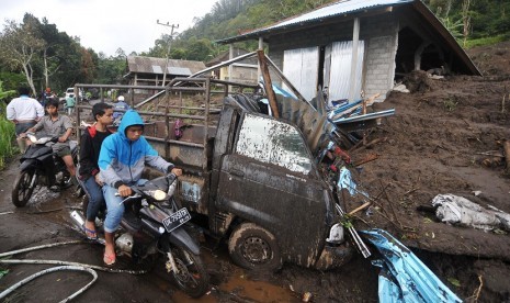 Sejumlah warga melintas di dekat rumah yang tersapu tanah longsor di Desa Songan, Kintamani, Bali, Jumat (10/2).