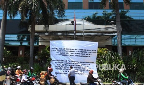 Sejumlah warga melintas di depan spanduk pengumuman penghentian operasional Hotel Alexis di Jalan RE Martadinata, Jakarta