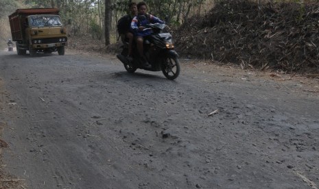 Sejumlah warga melintas di jalur evakuasi Merapi yang rusak di lereng gunung Merapi, Kemalang, Klaten, Jawa Tengah, Jumat (30/10).