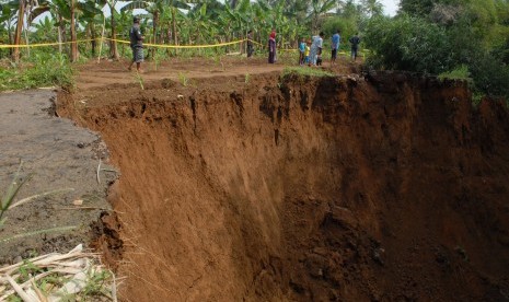 Sejumlah warga melintas di pinggiran jalan amblas di Kampung Pasir Angin, Caringin, Sukabumi, Jawa Barat, Selasa (17/5).