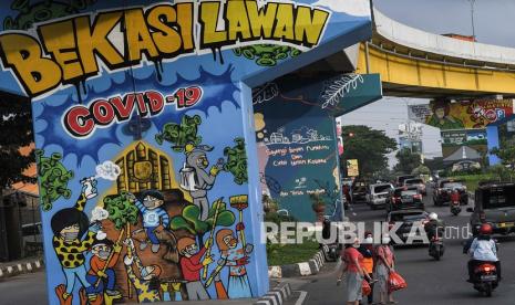 Sejumlah warga melintas disamping mural bertemakan sosialisasi untuk mencegah wabah COVID-19, Bekasi, Jawa Barat, Kamis (28/1/2021). Pemerintah Kota Bekasi memperpanjang Pemberlakuan Pembatasan Kegiatan Masyarakat (PPKM) hingga 30 hari untuk menurunkan kasus positif COVID-19.