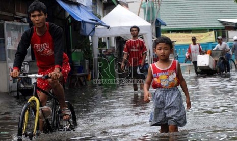  Sejumlah warga melintasi air banjir yang menggenangi pemukiman warga di Muara Angke, Jakarta Utara, Kamis (13/12).   (Republika/Agung Fatma Putra)