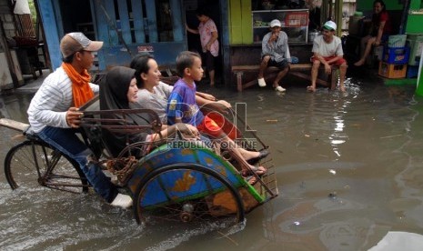  Sejumlah warga melintasi air banjir yang menggenangi pemukiman warga di Muara Angke, Jakarta Utara, Kamis (13/12).   (Republika/Agung Fatma Putra)