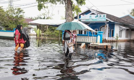 Sejumlah warga melintasi banjir (ilustrasi).