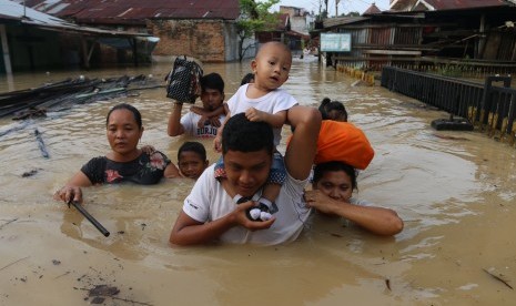 Sejumlah warga melintasi banjir yang merendam pemukiman penduduk di pinggiran Sungai Deli, Kecamatan Medan Maimun, Medan, Sumatera Utara, Selasa (7/11).