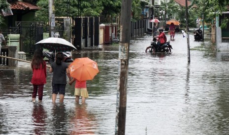 Sejumlah warga melintasi genangan air yang membanjiri jalan, di desa Mertasinga, Cilacap Utara, Cilacap, Jateng, Sabtu (7/10). Curah hujan ekstrim melanda Kabupaten Cilacap, dengan intensitas mencapai 298 mm, yang mengakibatkan banjir setinggi satu meter yang merendam ratusan rumah dan 420 jiwa terpaksa diungsikan, akibat genangan air yang memasuki rumah. 