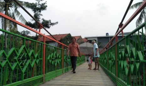 Sejumlah warga melintasi jembatan gantung 'Indiana Jones', di Kelurahan Srengseng Sawah, Kecamatan Jagakarsa, Kota Jakarta Selatan, Rabu (13/2).