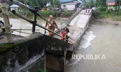 Sejumlah warga melintasi jembatan yang ambruk di Desa Sungai Pangkua, Kecamatan Koto Parik Gadang Diateh, Solok Selatan, Sumatera Barat, Selasa (26/11/2019). 