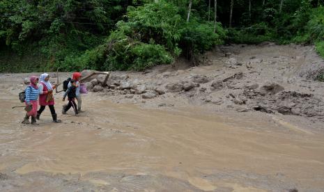 Sejumlah warga melintasi material lumpur akibat longsor di jalur alternatif Cijapati, Kadungora, Kabupaten Garut, Jawa Barat, Kamis (25/3/2021). Hujan deras disertai kondisi tanah yang gembur menjadi penyebab tanah longsor yang menutupi jalan penghubung antara Kabupaten Bandung dan Kabupaten Garut.