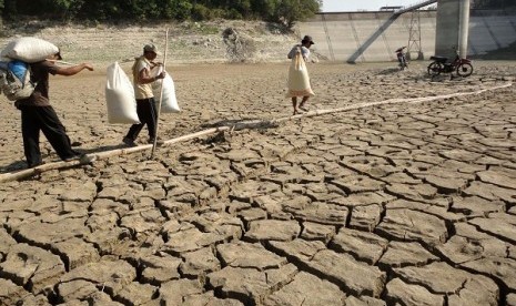 Sejumlah warga membawa hasil pertanian melintas di tanah yang kering di Waduk Pacal, Bojonegoro, Jawa Timur, Kamis (30/8). 