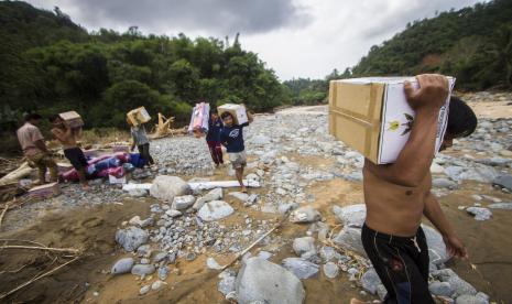 Sejumlah warga membawa logistik bantuan banjir bandang di Desa Datar Ajab, Kabupaten Hulu Sungai Tengah, Kalimantan Selatan, Ahad (24/1/2021). Bantuan berupa tenda, sembako serta perlatan dapur dari TNI Angkatan Udara Lanud Sjamsudin Noor, Dharma Pertiwi Peduli, Kepala Staf Angkatan Udara dan Badan Penanggulangan Bencana Daerah (BPBD) Provinsi Kalsel itu didistribusikan melalui jalur udara ke wilayah pedalaman pegunungan Meratus.