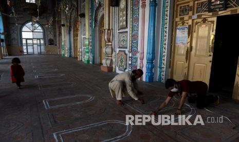 Sejumlah warga memberikan tanda tempat bagi para jamaah untuk menjaga jarak selama shalat di masjid saat menjelang bulan puasa Ramadhan di Rawalpindi, Pakistan, Kamis (23/4). Ramadhan dimulai akhir pekan ini, Muslim Muslim di seluruh dunia berusaha mencari cara bagaimana mempertahankan ritual paling dihargai di bulan yang paling suci. 