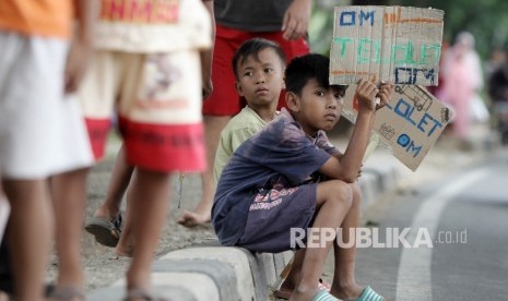 Sejumlah warga memegang poster bertuliskan Om Telolet Om saat menanti bus yang melintas membunyikan Klakson Telolet di Jalan Raya Bogor, Jakarta TImur, Ahad (25/12). 