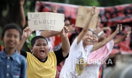 Sejumlah warga memegang poster bertuliskan Om Telolet Om saat menanti bus yang melintas membunyikan Klakson Telolet di Jalan Raya Bogor, Jakarta TImur, Ahad (25/12). 