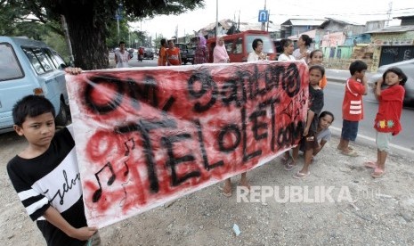 Sejumlah warga memegang poster bertuliskan Om Telolet Om saat menanti bus yang melintas membunyikan Klakson Telolet di Jalan Raya Bogor, Jakarta TImur, Ahad (25/12).