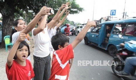 Sejumlah warga memegang poster bertuliskan Om Telolet Om saat menanti bus yang melintas membunyikan Klakson Telolet di Jalan Raya Bogor, Jakarta TImur, Ahad (25/12).