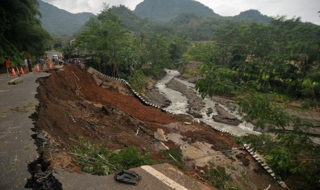 Sejumlah warga memperhatikan jalan longsor di Desa Sendanghela, Brebes, Jawa Tengah, Senin (23/1).