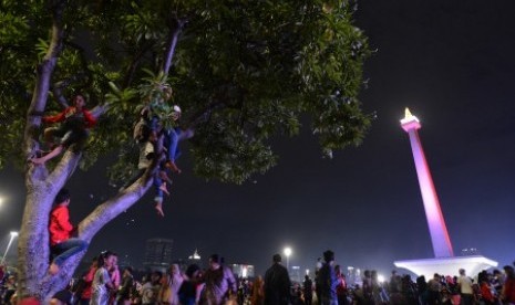 Sejumlah warga menaiki pohon untuk menyaksikan hiburan dalam rangka menyambut pergantian tahun di Monas, Jakarta, Ahad (31/12). 