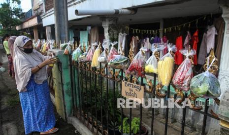 Sejumlah warga mengambil berbagai sayuran yang digantung pada pagar rumah di Gang Palautan, Cilodong, Depok, Jawa Barat, Jumat (21/1/2022). Warga Rt 04 Rw 01 di kawasan tersebut secara swadaya berbagi sayuran, beras, dan bumbu masak secara gratis setiap hari Jumat sebagai bentuk aksi solidaritas kepada warga lainnya yang terdampak pandemi COVID-19. 