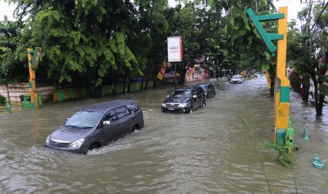 Sejumlah warga mengendarai mobil menembus banjir yang merendam Jalan dr Mansyur, di Medan, Sumatra Utara, Senin (9/7).