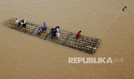 Sejumlah warga menggunakan jasa rakit bambu untuk melintasi sungai Krueng Meureubo yang menghubungkan Desa Meunuang Kinco dengan Desa Alue Keumang Kecamatan Pante Ceureumen, Aceh Barat, Aceh, Sabtu (11/12/2021). Pascarusaknya jembatan gantung penghubung desa pada Desember 2018 lalu, masyarakat setempat terpaksa menggunakan jasa rakit bambu untuk mempersingkat jarak tempuh hingga 10 kilometer akibat belum adanya perbaikan jembatan dari pihak terkait. 