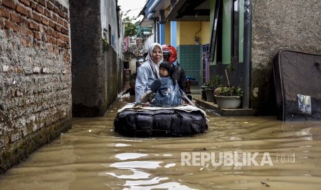 Sejumlah warga menggunakan rakit melintasi genangan banjir di Kampung Bojongasih, Kecamatan Dayeuhkolot, Kabupaten Bandung, Jumat (24/1).