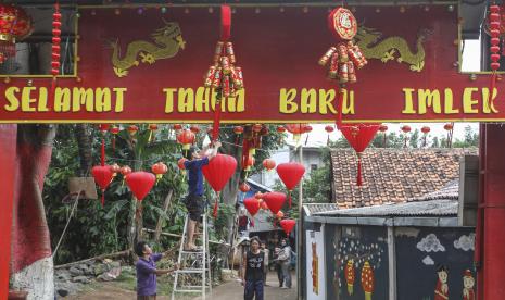 Sejumlah warga menghias jalan dengan lampion di Jalan H Bona, Limo, Depok, Jawa Barat, Rabu (26/1/2022). Kampung dengan sejumlah warga keturunan Tionghoa tersebut menyambut perayaan Tahun Baru Imlek 2022 dengan menghias gapura dan jalan dengan pernak-pernik imlek. 