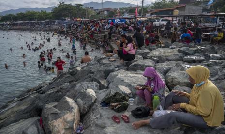 Sejumlah warga menikmati suasana di kawasan wisata Pantai Kampung Nelayan, Palu, Sulawesi Tengah, Ahad (6/2/2022). Satgas COVID-19 setempat mengimbau warga untuk tetap mematuhi protokol kesehatan agar terhindar dari risiko terinfeksi, terutama varian Omicron tak terkecuali di tempat-tempat wisata.  Kemenkes: Pasien Positif Covid-19 tanpa Gejala Cukup Isoman