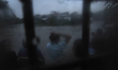 Sejumlah warga menonton banjir yang melanda bantaran sungai Ciliwung di kawasan Kampung Melayu, Jakarta, Selasa (15/1).