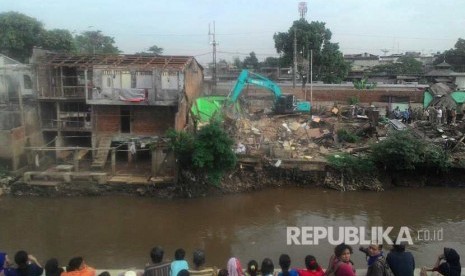 Sejumlah warga menyaksikan alat berat membongkar sejumlah bangunan di Bukit Duri, Rabu (28/9).