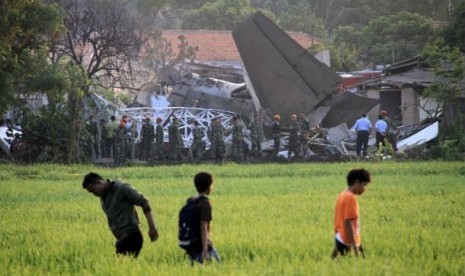  Sejumlah warga menyaksikan bangkai pesawat Fokker 27 yang terjatuh di komplek Rajawali, Lapangan Udara Halim Perdana Kusuma, Jakarta, Kamis (21/6). 