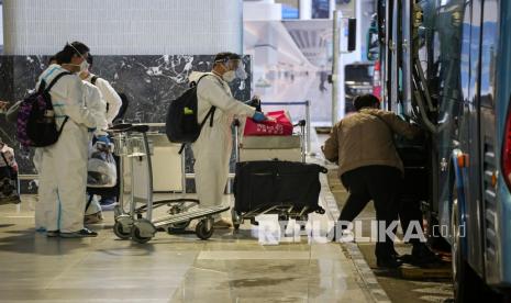 Sejumlah warga negara asing (WNA) dengan menggunakan baju hazmat memasukkan barang bawaannya ke dalam bus saat hendak menuju tempat karantina setibanya di Bandara Internasional Soekarno Hatta, Tangerang, Banten.