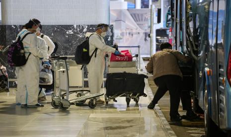 Sejumlah warga negara asing (WNA) dengan menggunakan baju hazmat memasukkan barang bawaannya ke dalam bus saat hendak menuju tempat karantina setibanya di Bandara Internasional Soekarno Hatta, Tangerang, Banten.