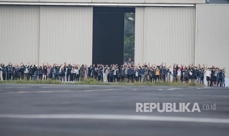 Sejumlah Warga Negara Indonesia (WNI) yang dievakuasi dari Wuhan, Hubei, China melambaikan tangan kearah media saat akan melakukan senam bersama prajurit TNI pada hari ketigabelas di Hanggar Pangkalan Udara TNI AU Raden Sadjad, Ranai, Natuna, Kepulauan Riau, Jumat (14/2/2020).